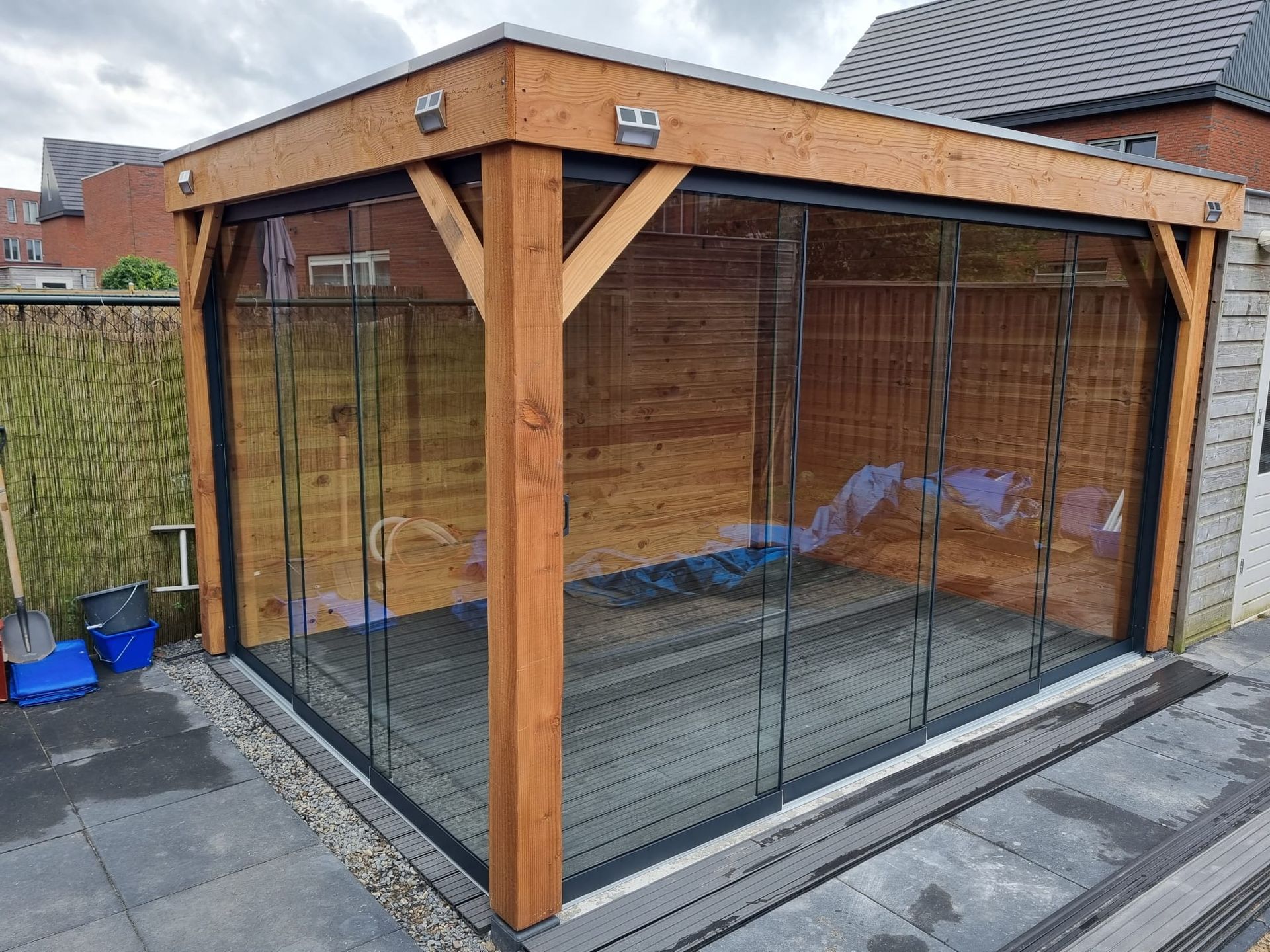 Een houten schuur met glazen schuifdeuren in een achtertuin.