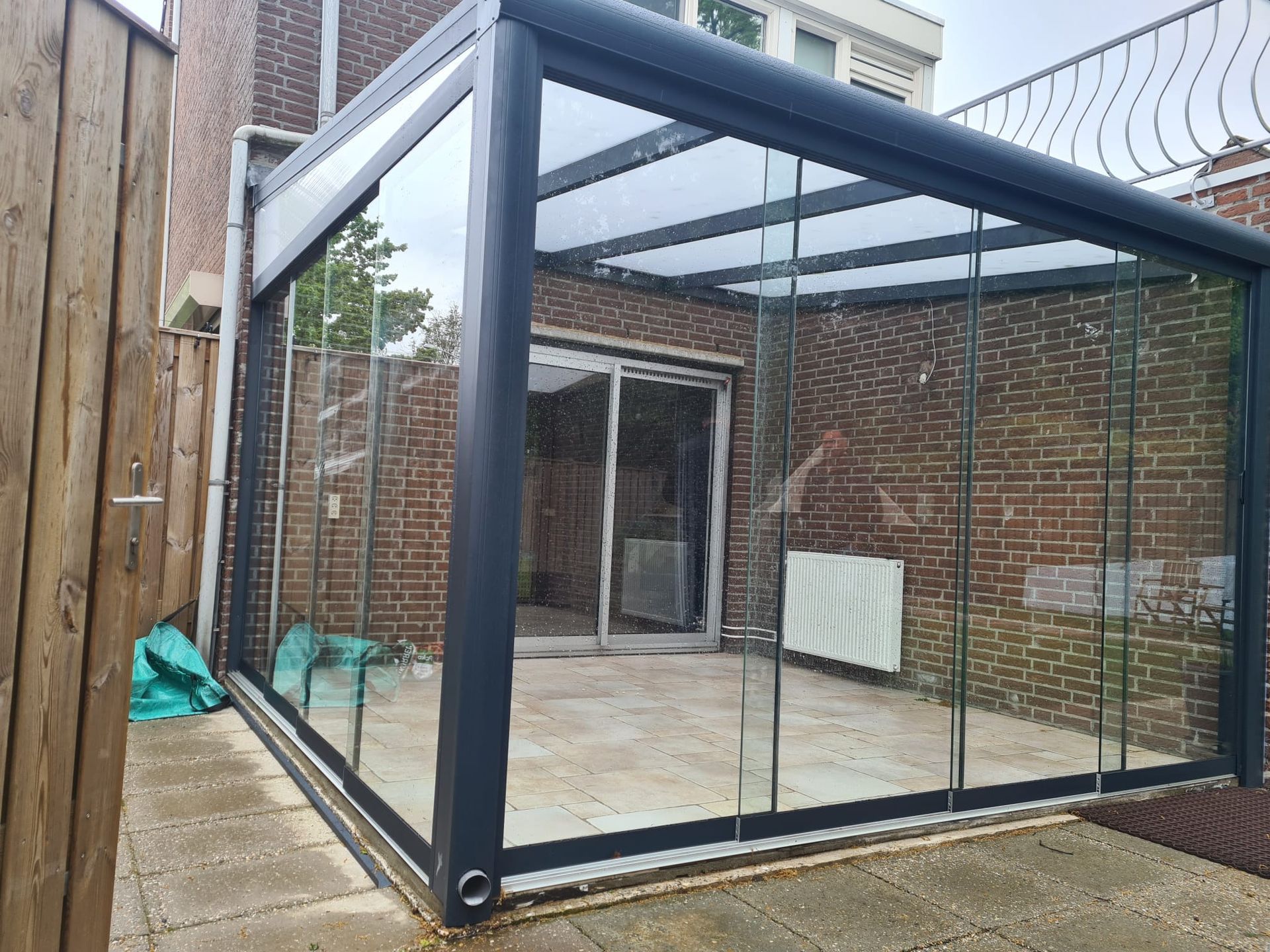 Een patio met een glazen dak en glazen schuifdeuren.