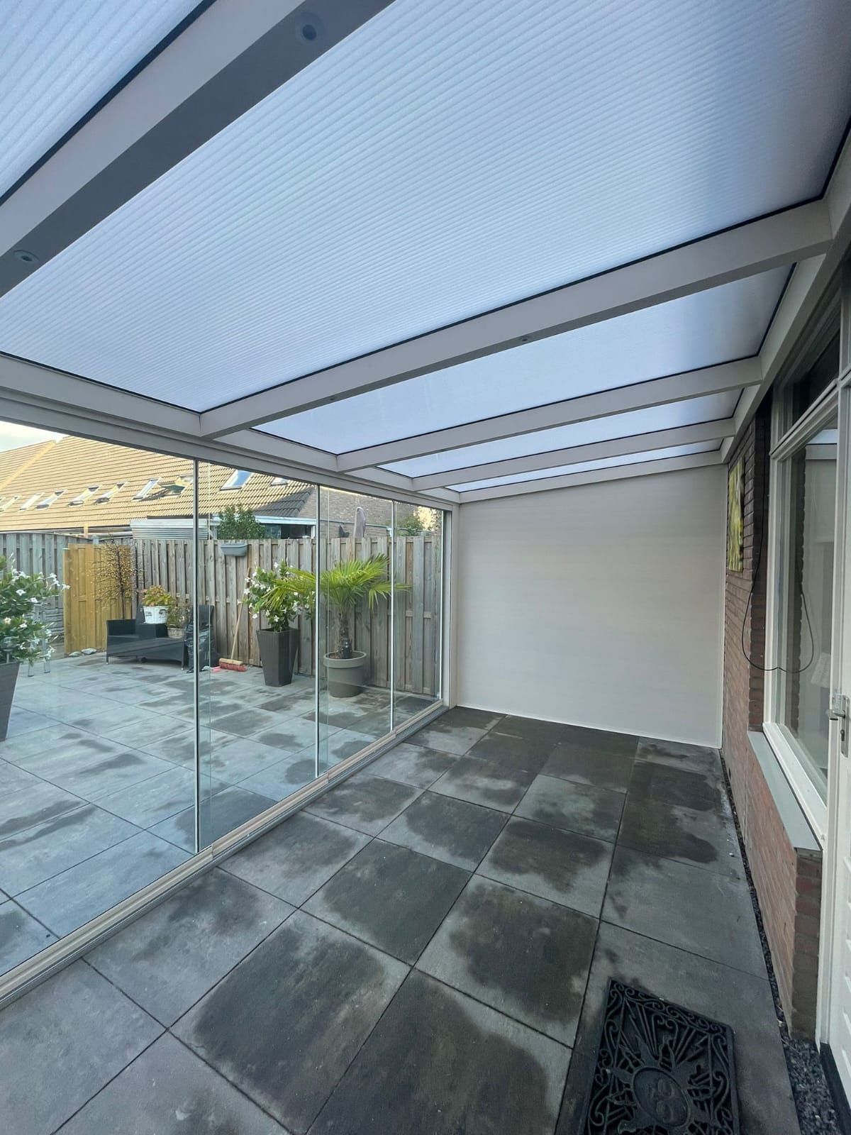 Een kamer met een glazen dak en een patio op de achtergrond.