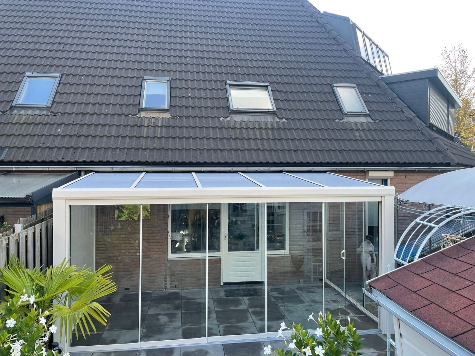 De achterkant van een huis met een glazen terras en een dakraam op het dak.