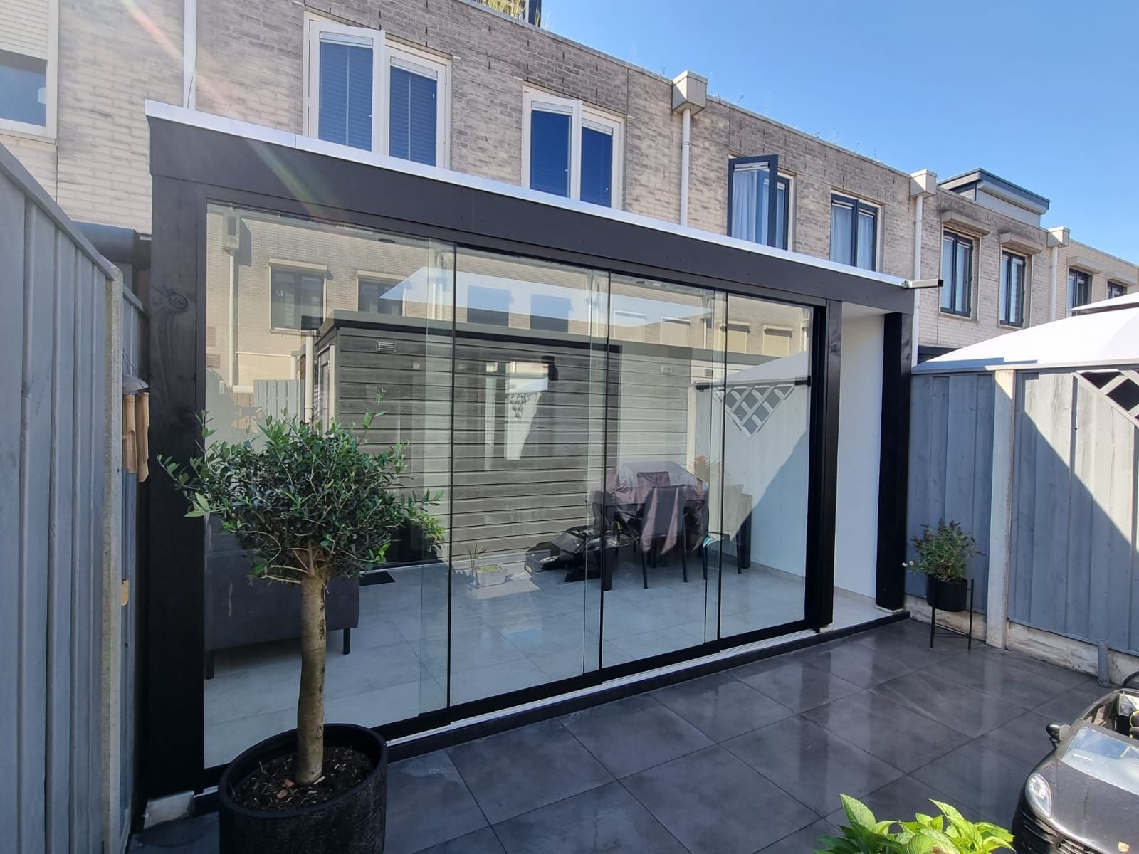 Een huis met veel ramen en een boom ervoor.