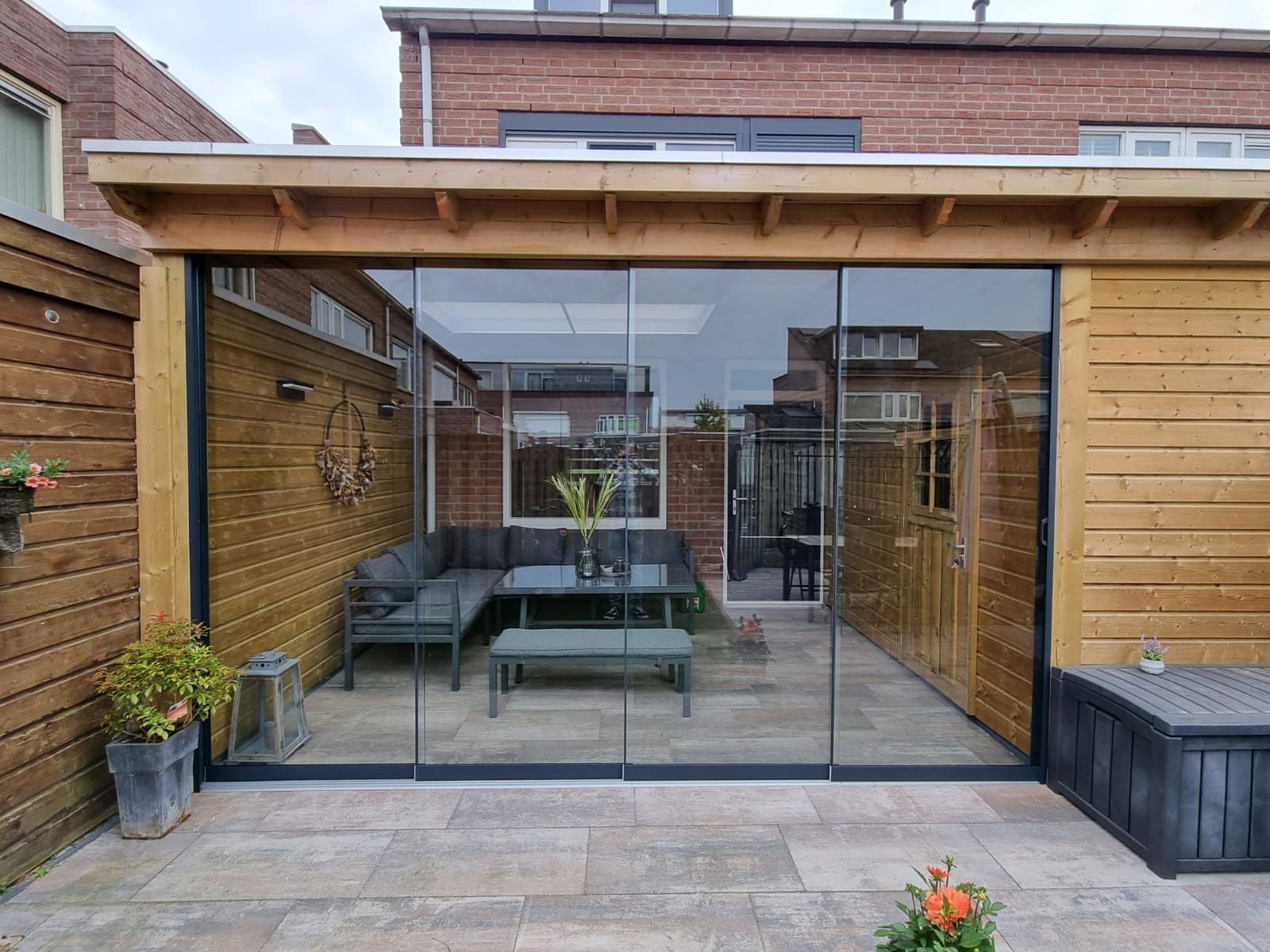 Een patio met glazen schuifdeuren en een houten dak.