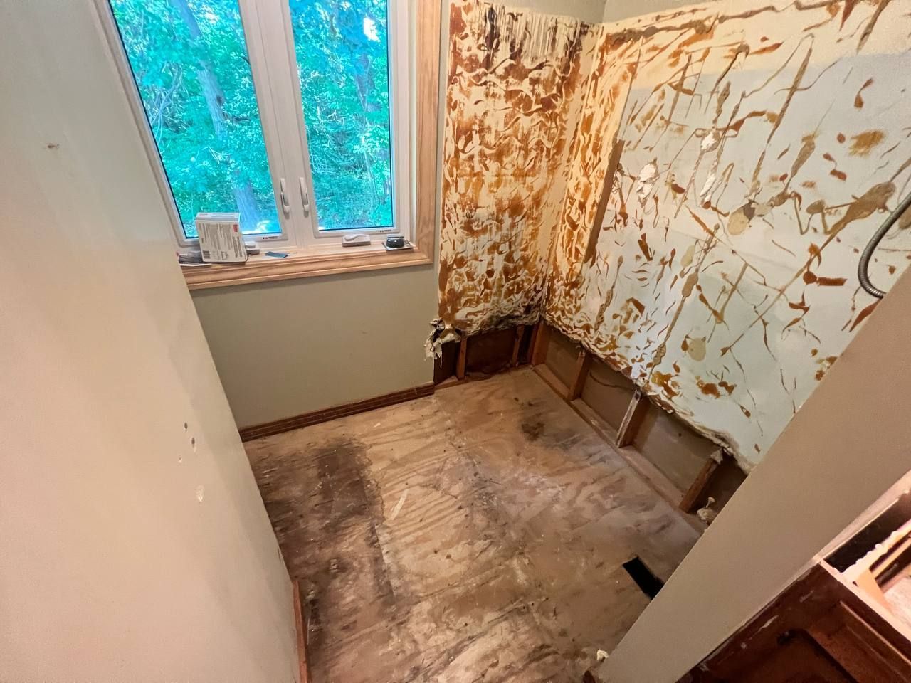 A bathroom with a window and a dirty floor.