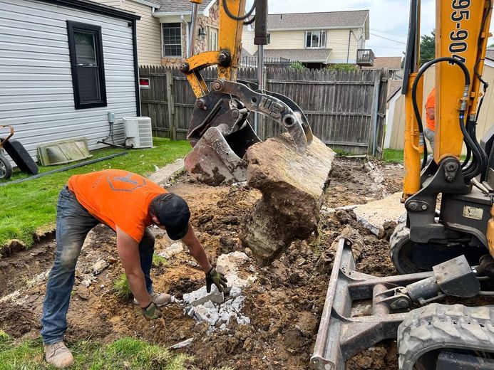 A man is digging a hole in the dirt in front of a house.