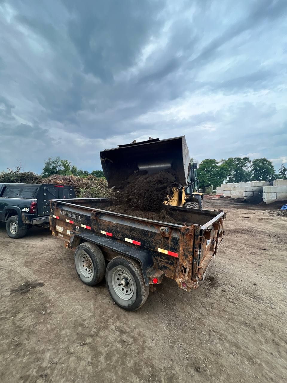 A dump truck is being loaded with dirt on a trailer.