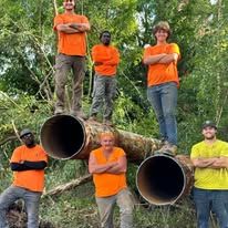 A group of people are standing on top of a pile of pipes.