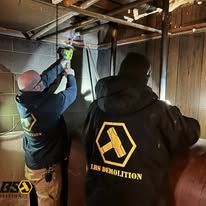 Two men are working on a pipe in a basement.