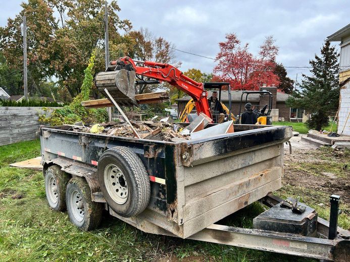 A trailer with a bulldozer on it is sitting in the grass.