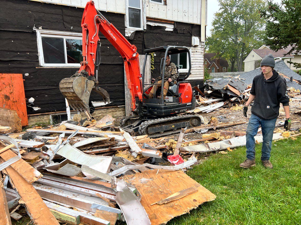 A man is standing in front of a house that is being demolished.