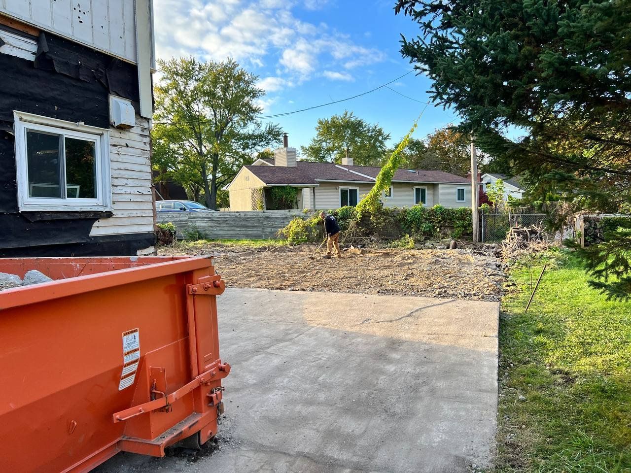 A dumpster is parked in front of a house.