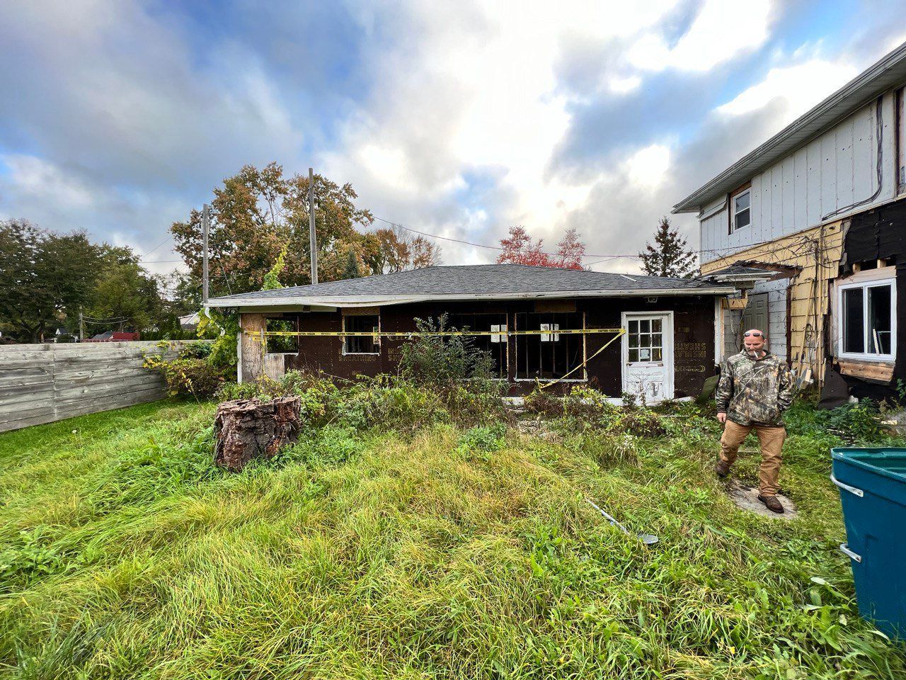 A man is standing in the grass in front of a house.