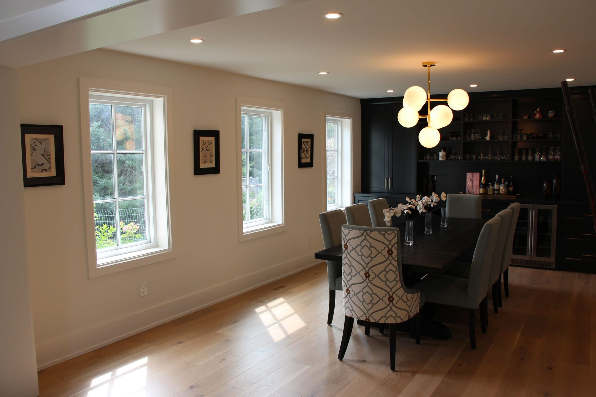 Dining room with a table set for guests, light wood floors, and windows.