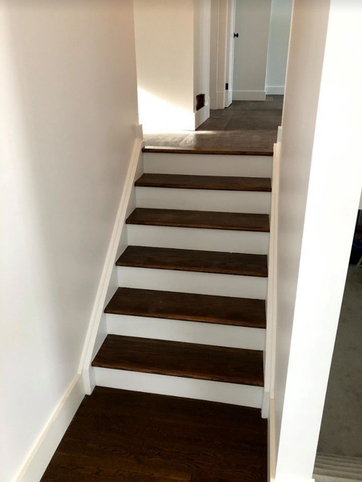 Dark wood stairs with white risers and trim, leading to a hallway with doors.