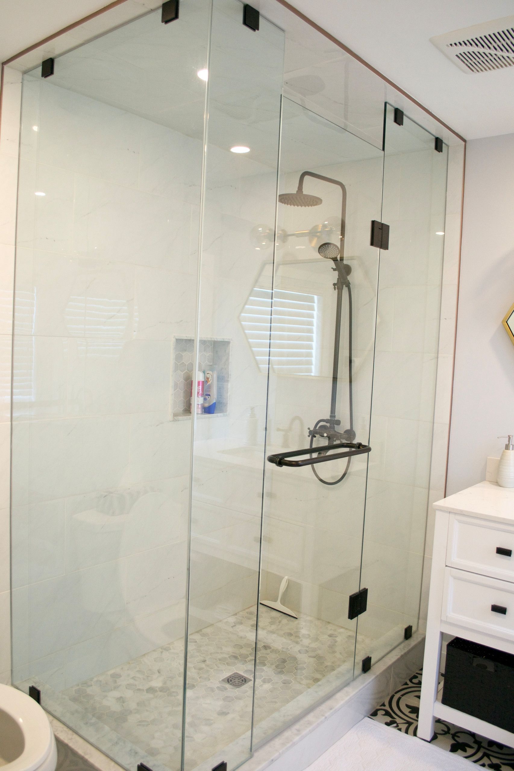Glass shower with black fixtures and white walls.