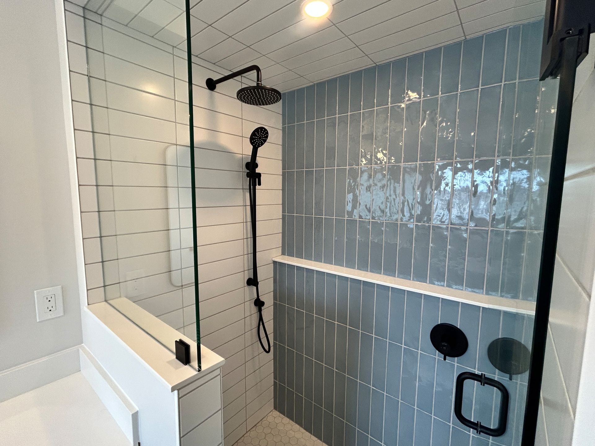 Shower with blue and white tile, black fixtures, and glass door.