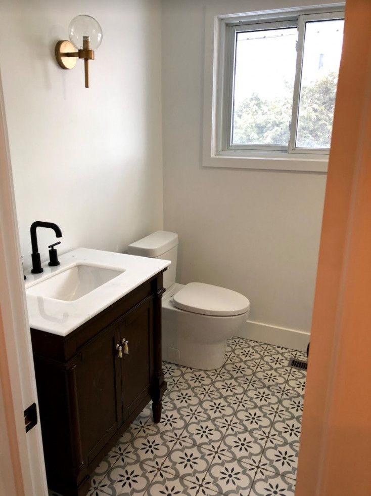 Bathroom with dark vanity, black faucet, patterned floor tiles, and a window.
