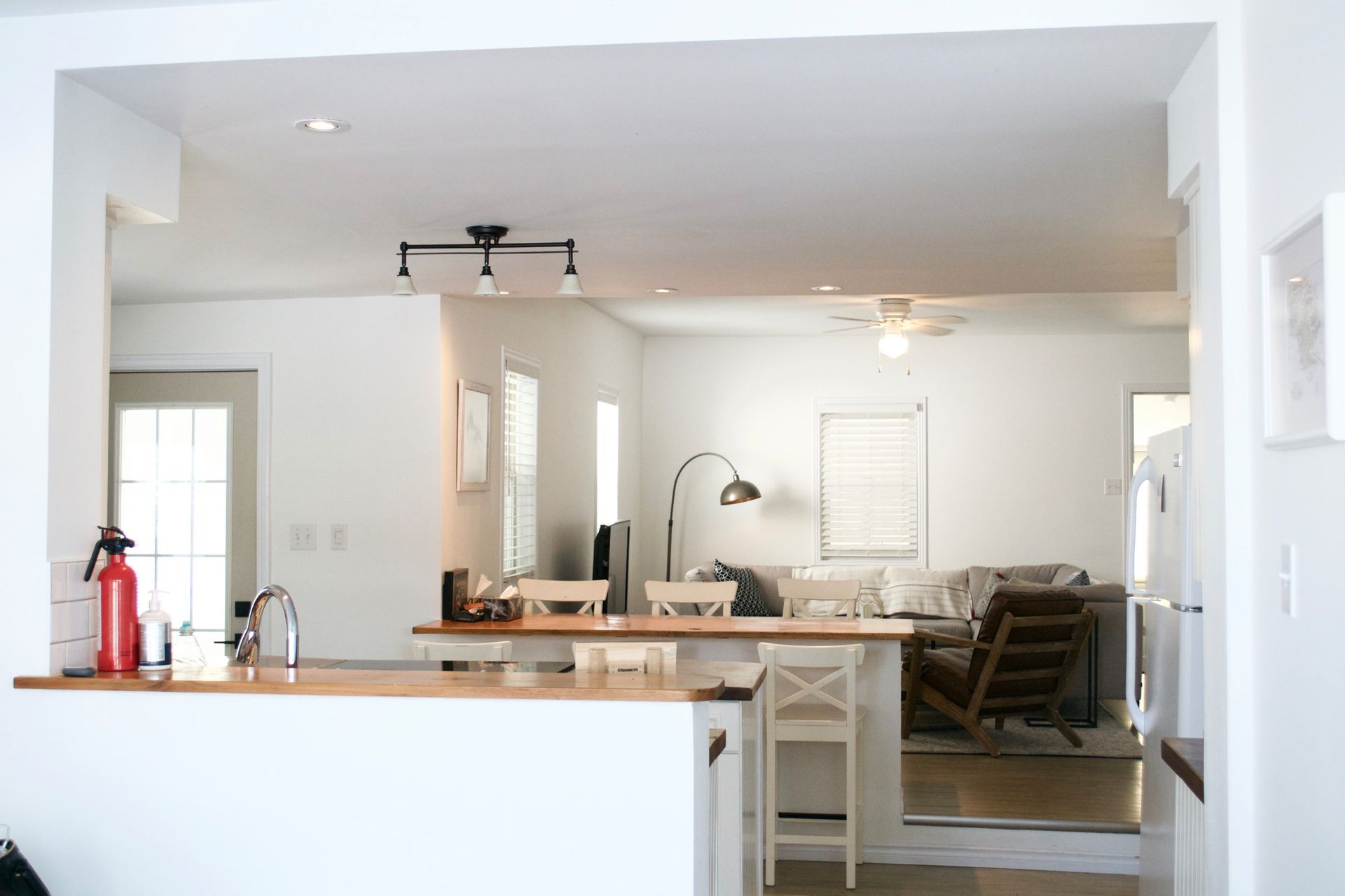 Open-concept kitchen with a light wood countertop and a view into the living room.
