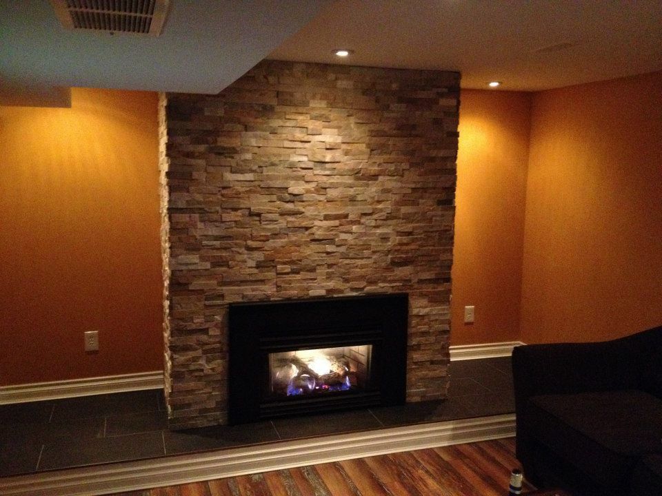 Fireplace with stone facade in a room with orange walls and dark flooring.