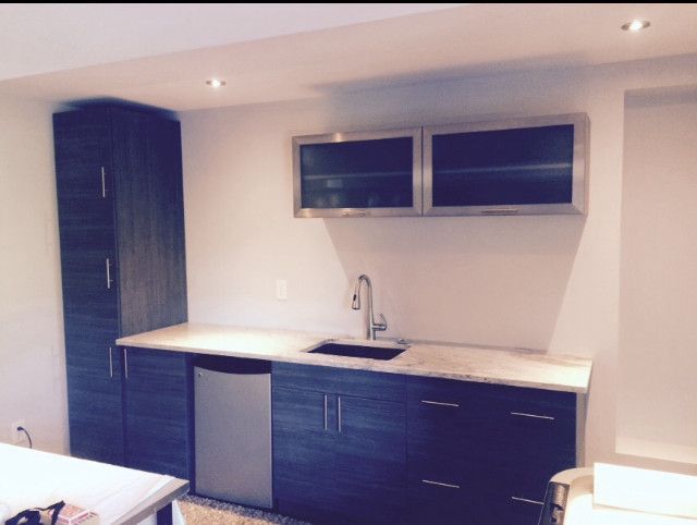 Dark wood cabinets and countertop with sink, faucet, and stainless steel upper cabinets in a small kitchen space.