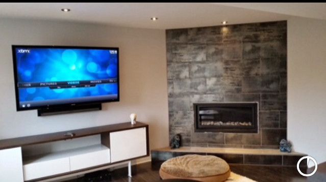 Modern living room with a wall-mounted TV, fireplace, and white and wood furniture.