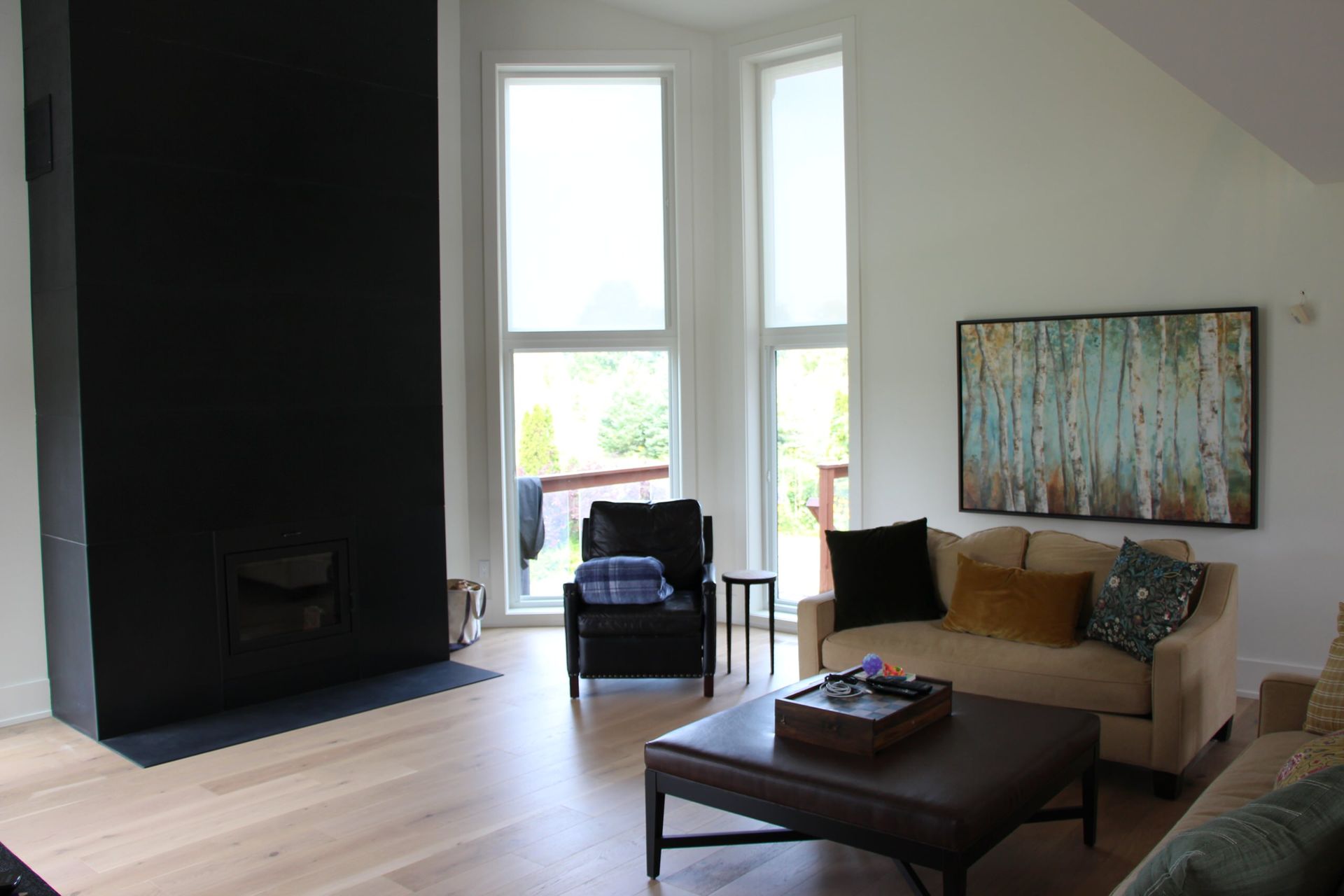 Living room with black fireplace, tall windows, and tan sofa.