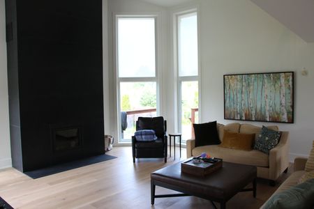 Living room with black fireplace, tall windows, and tan sofa.