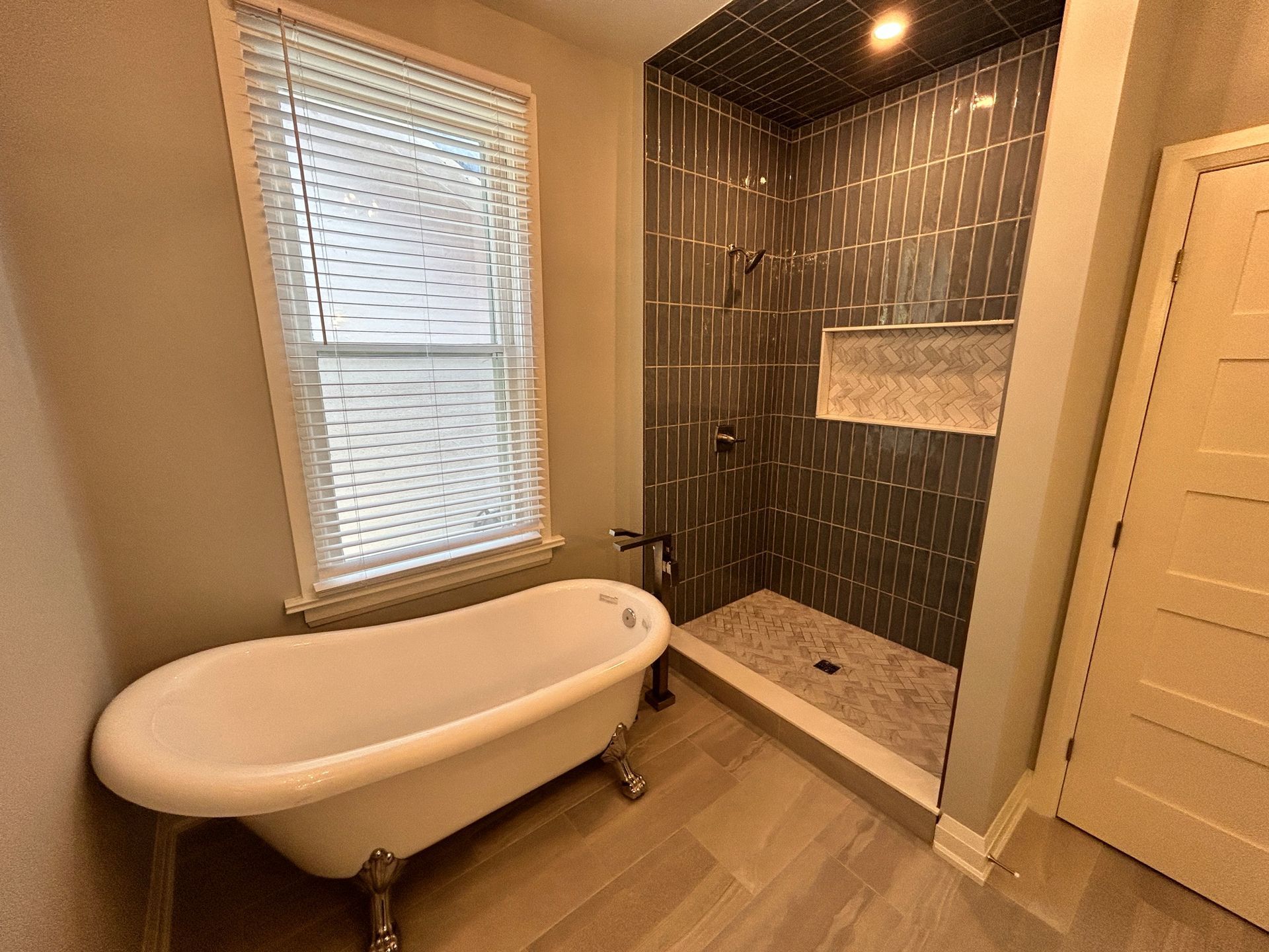 Bathroom with a claw-foot tub near a window, tiled shower, and door.