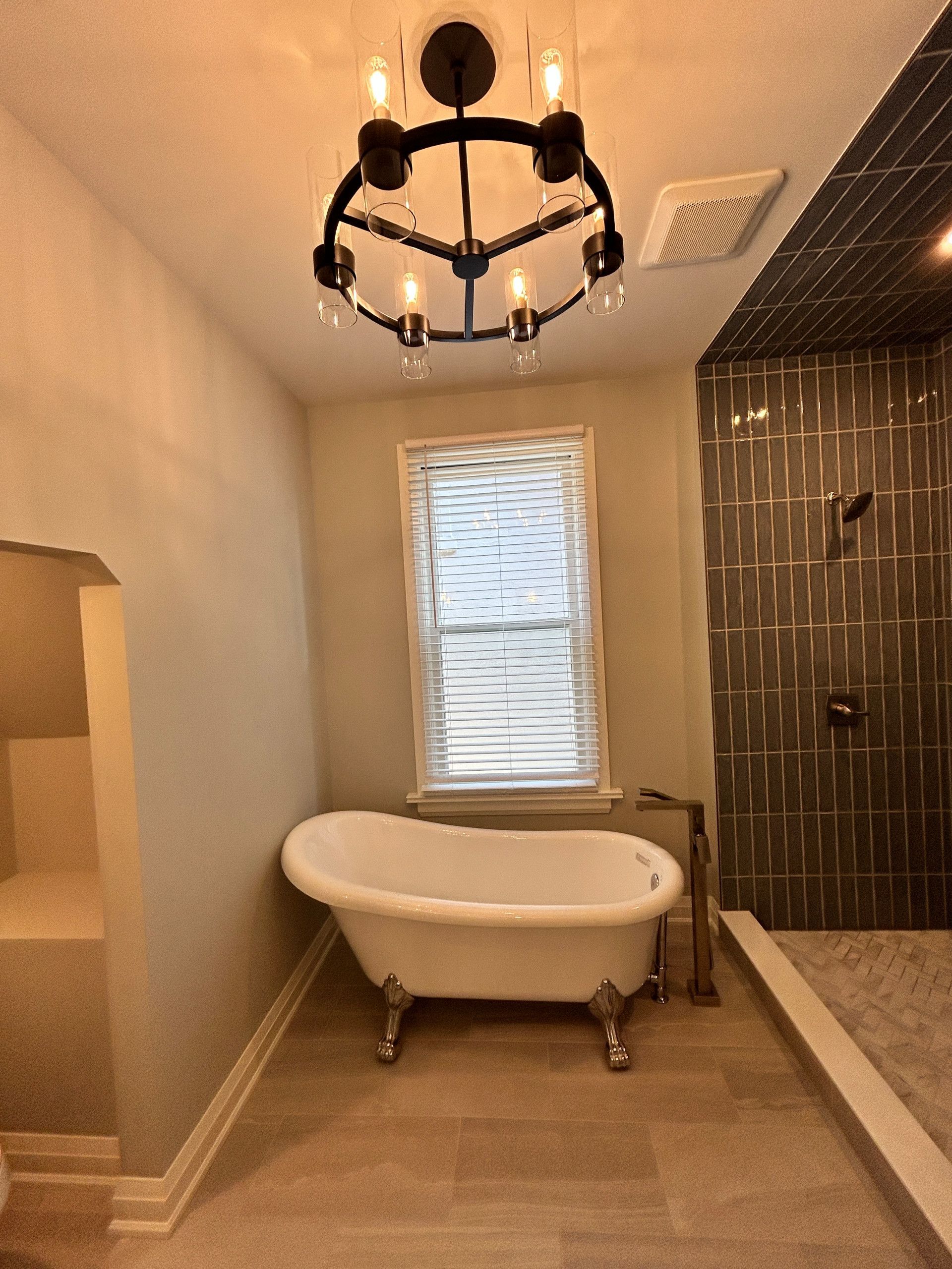 Bathroom with a clawfoot tub, dark shower, and a circular chandelier.