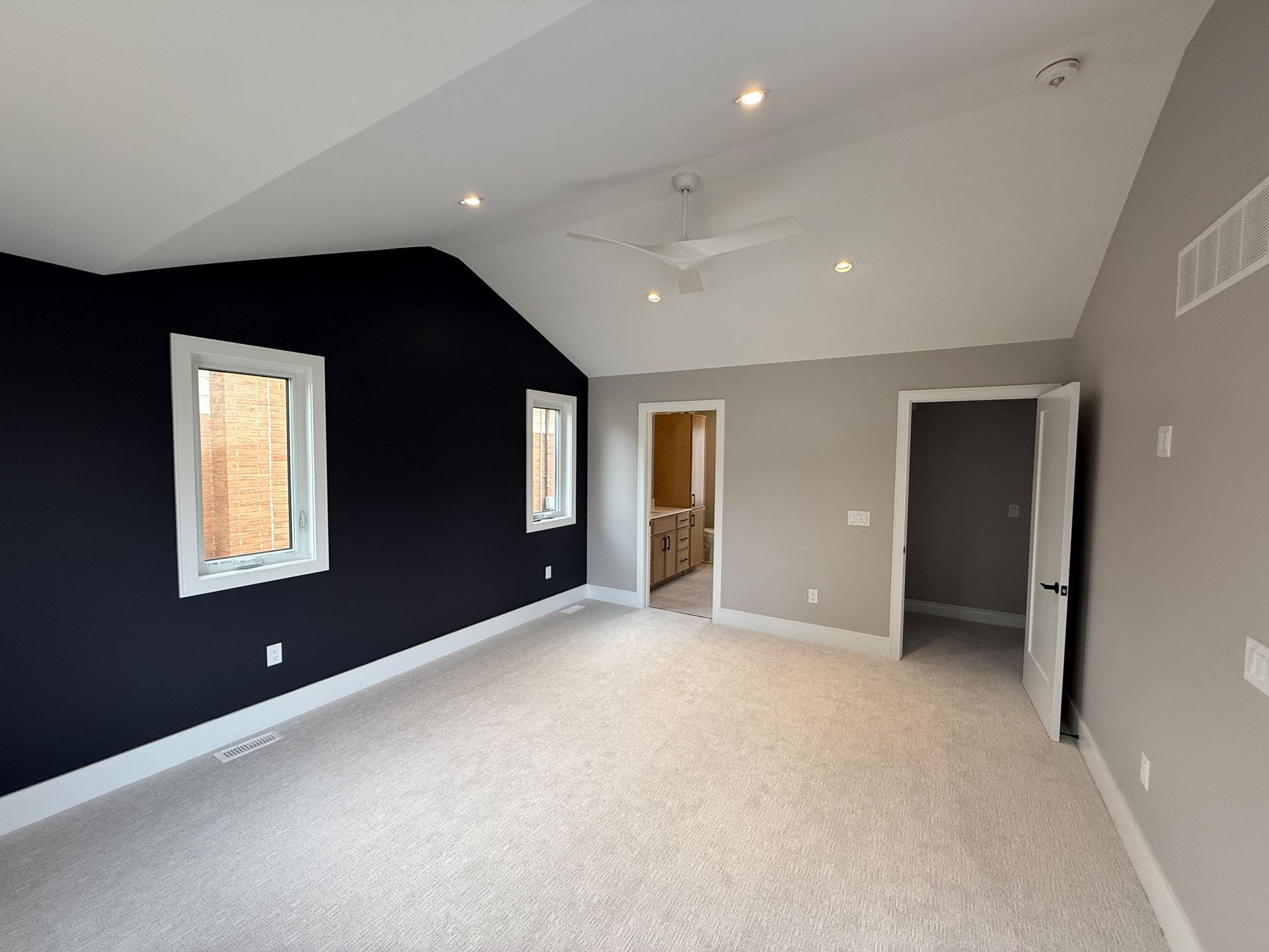 Bedroom with navy accent wall, light gray walls, carpet, and open doorway.