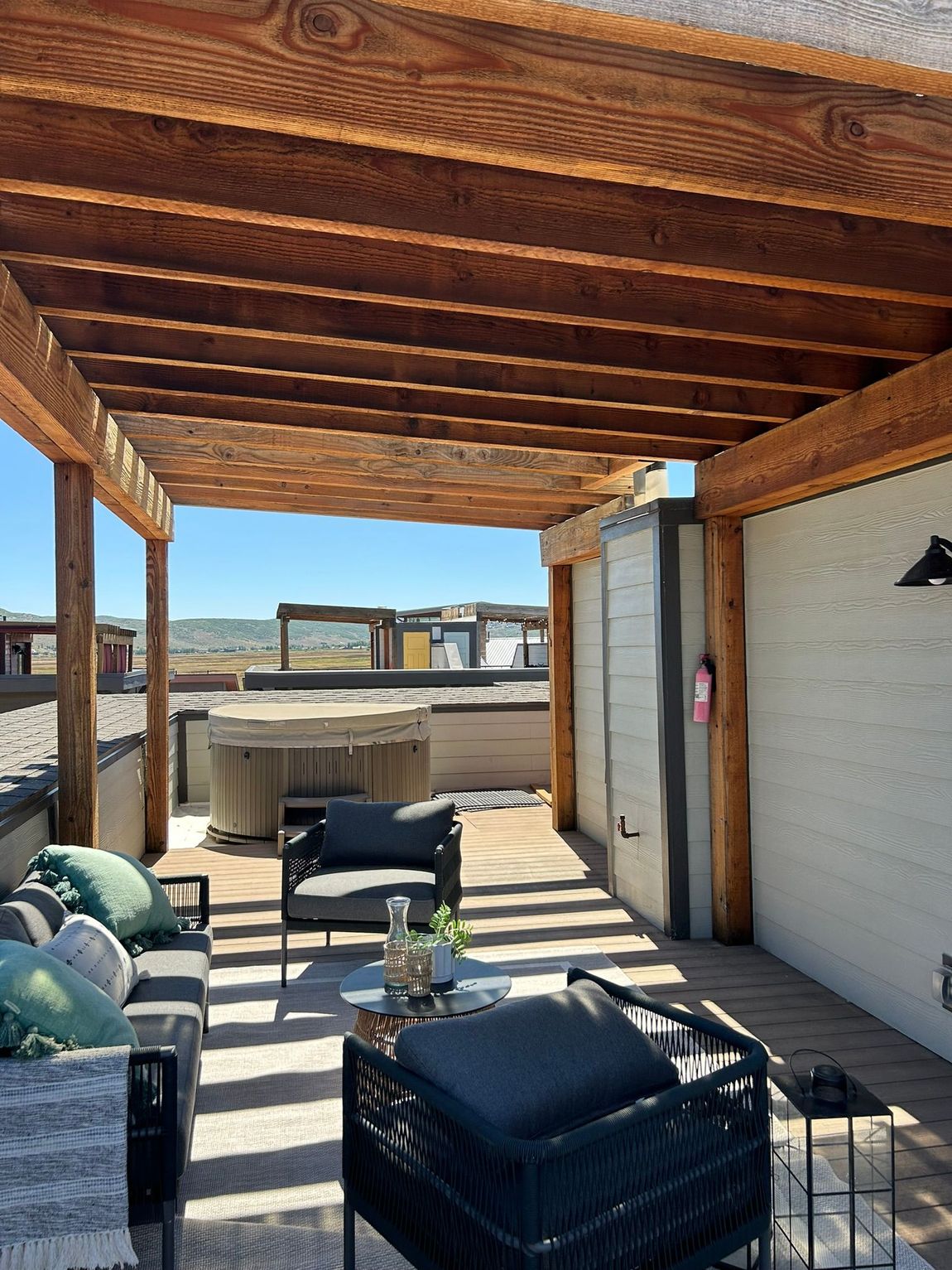 A patio with a pergola , chairs , a table and a hot tub.