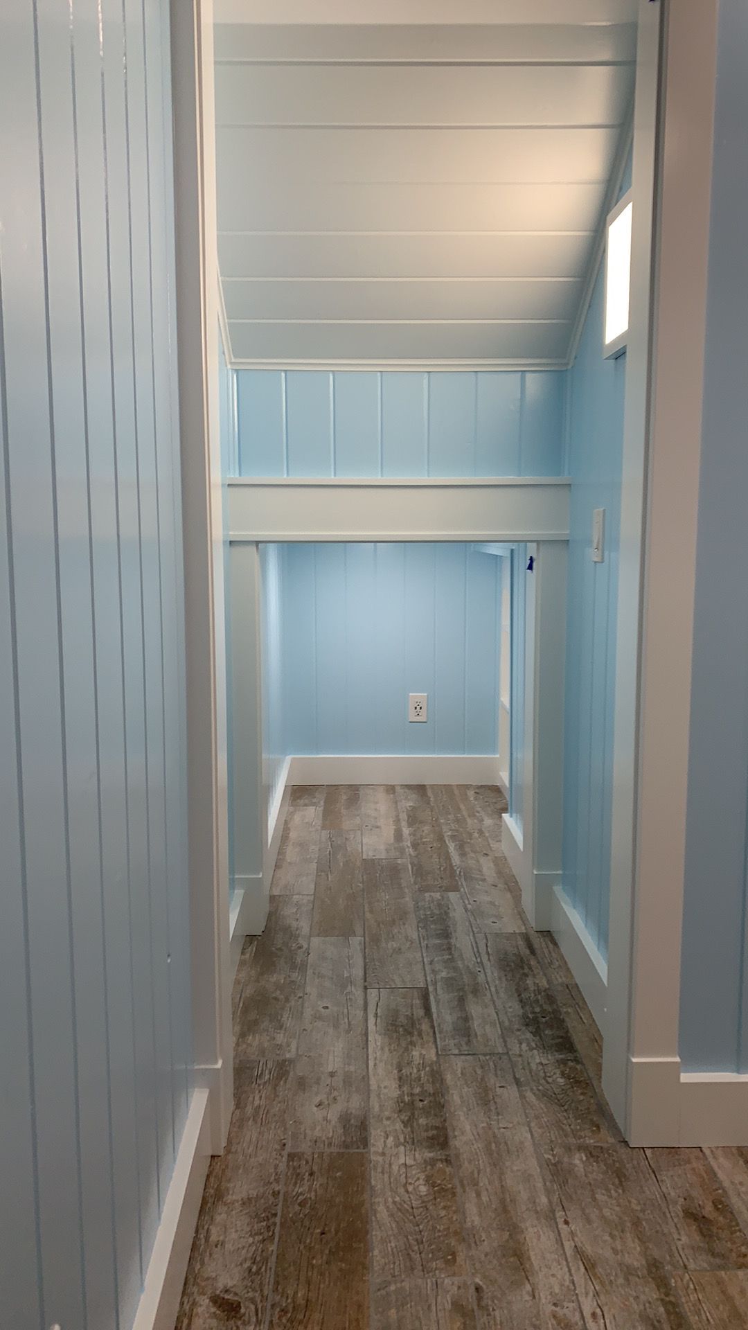 A hallway with blue walls and wooden floors in a house.