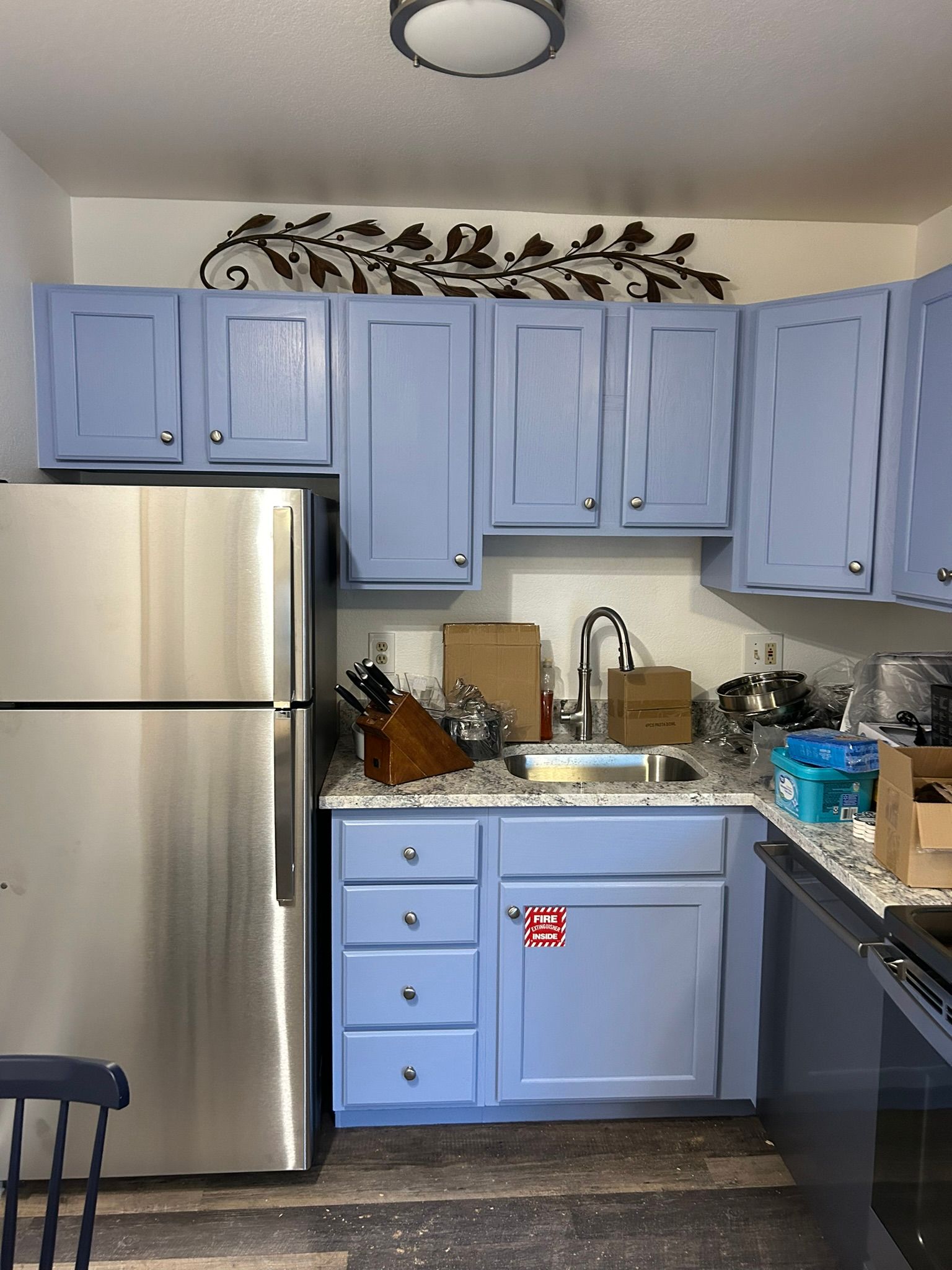 A kitchen with blue cabinets and a stainless steel refrigerator