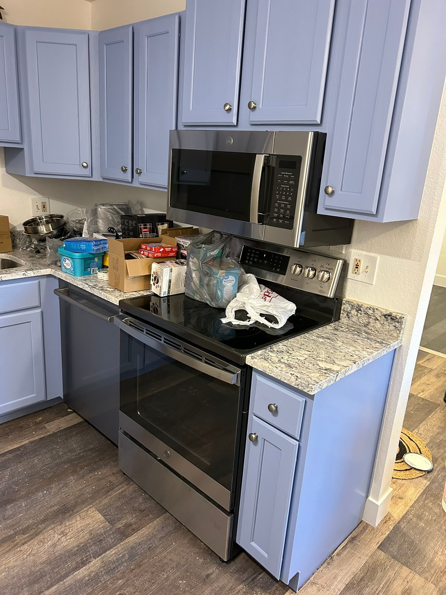 A kitchen with blue cabinets , stainless steel appliances , and granite counter tops.