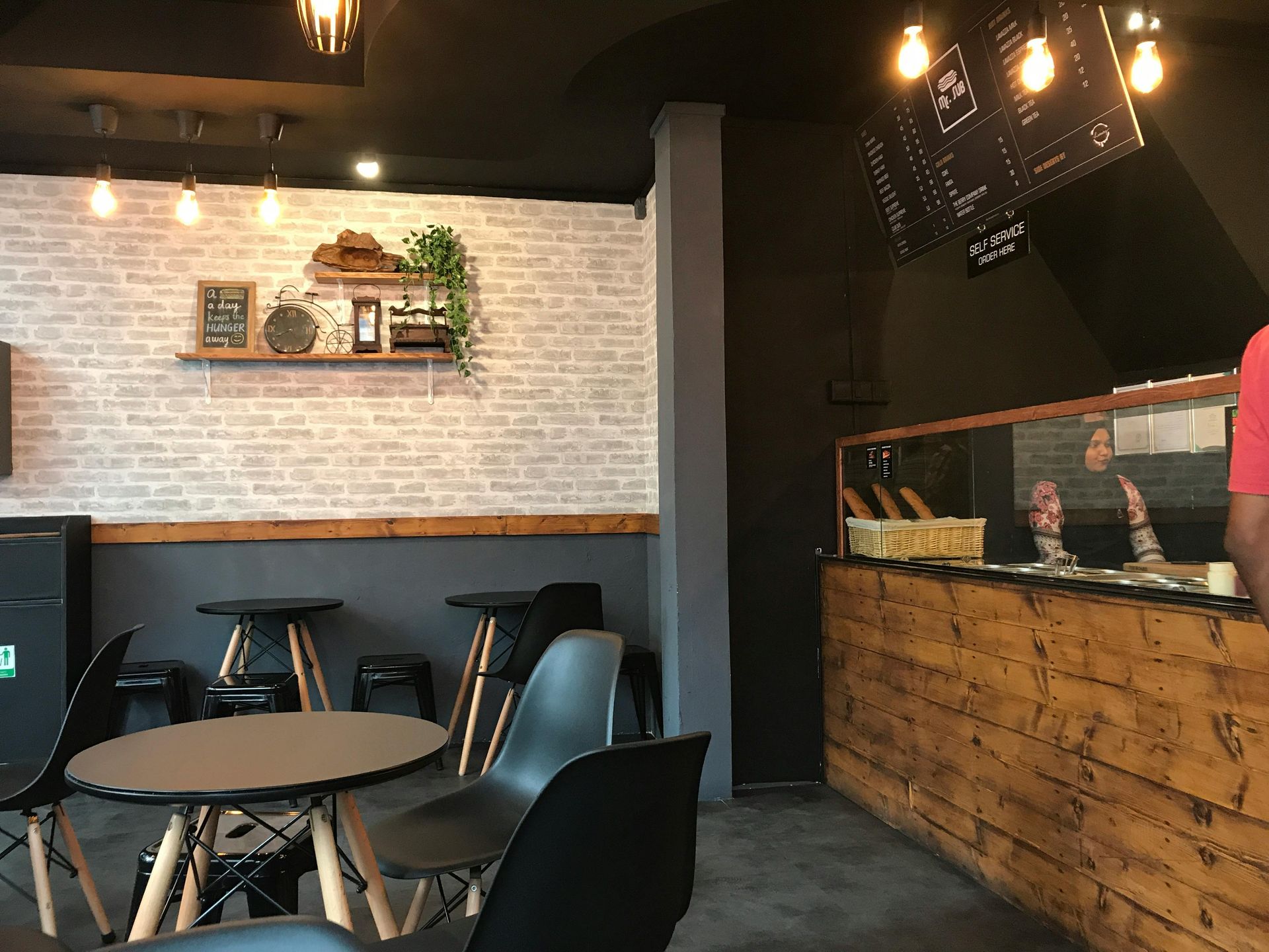 A restaurant with tables and chairs and a menu on the wall.