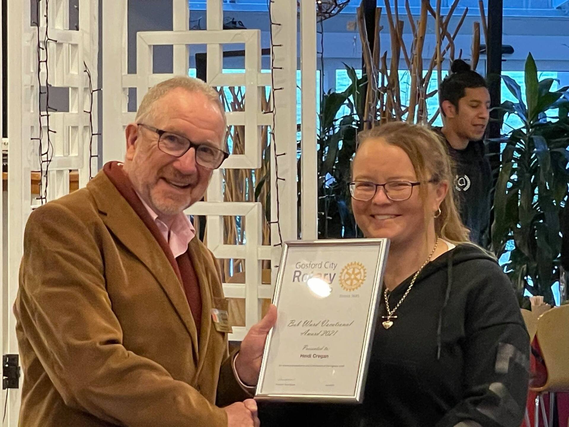A man and a woman are shaking hands while holding a certificate.