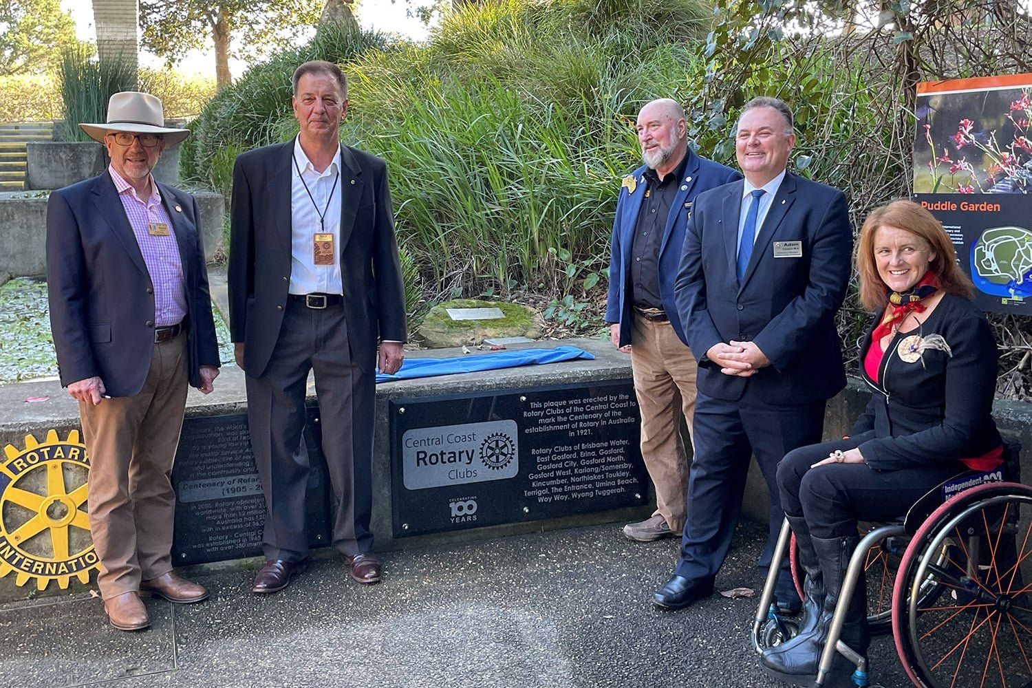 A group of people are standing next to each other in front of a plaque.