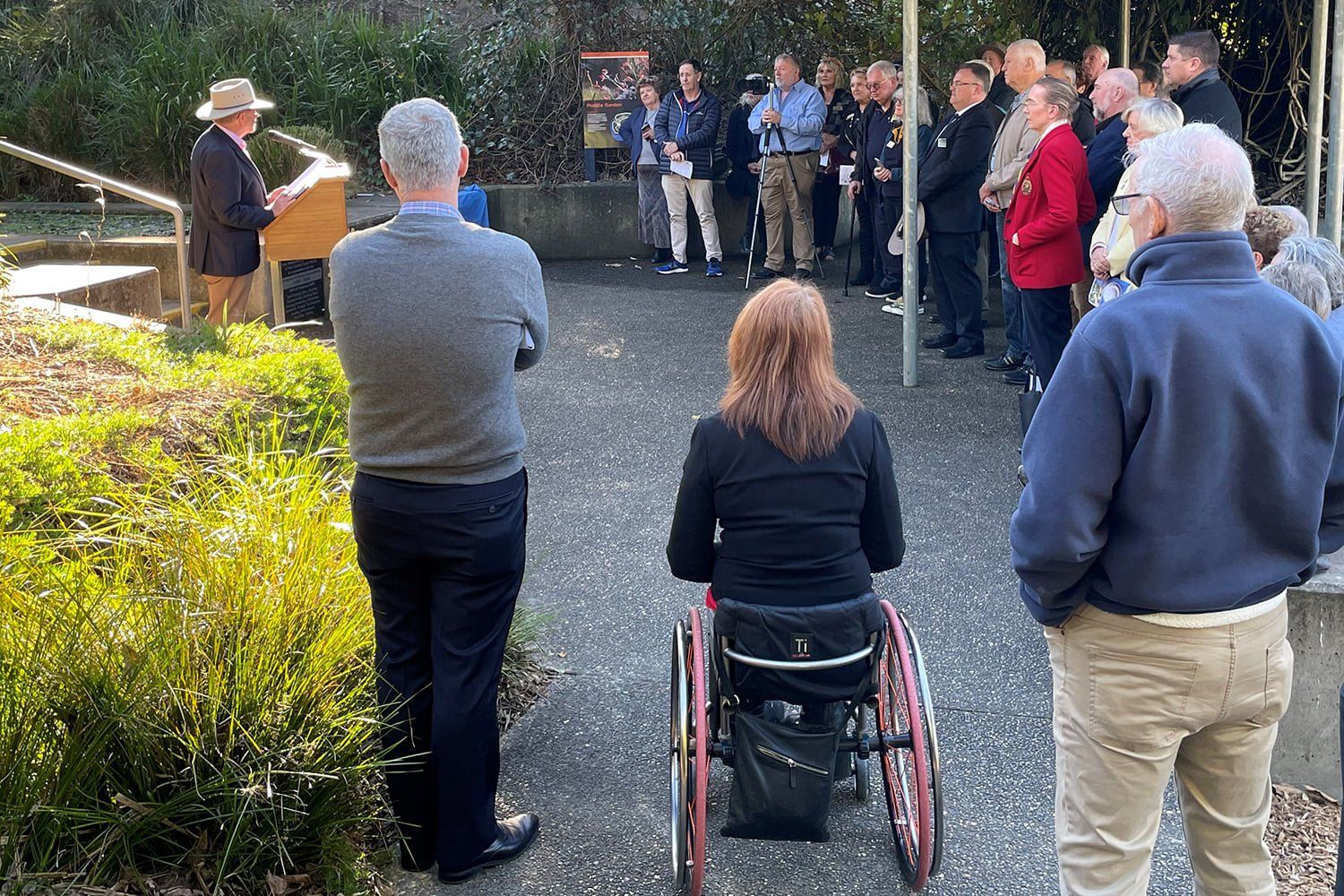 A woman in a wheelchair is sitting in front of a crowd of people.