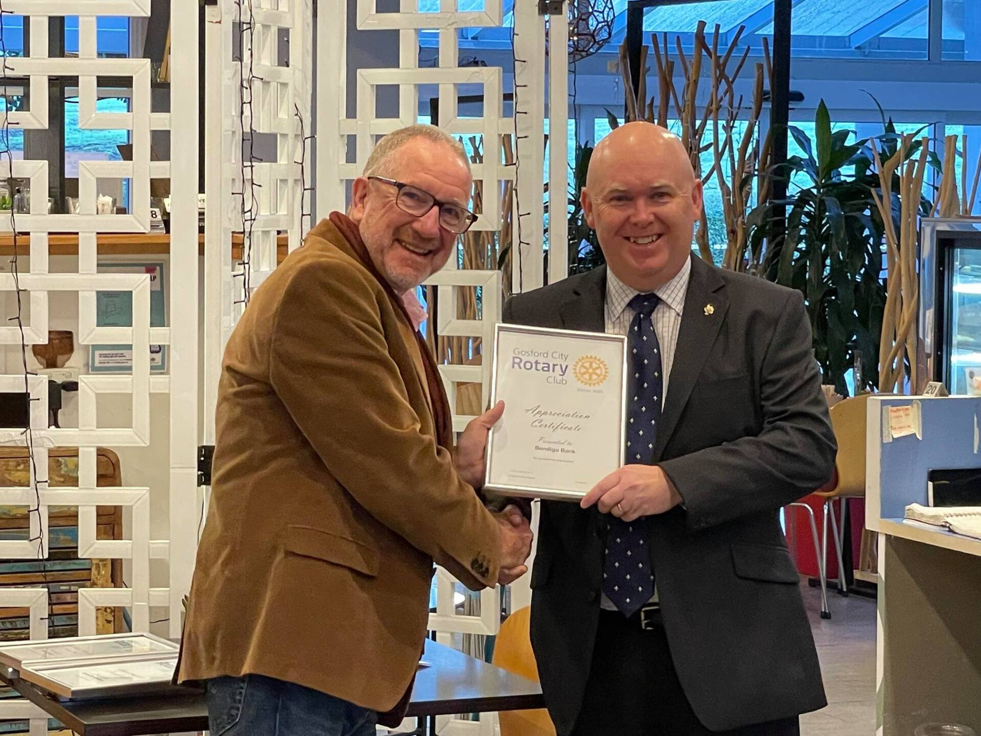 Two men are shaking hands and holding a certificate.