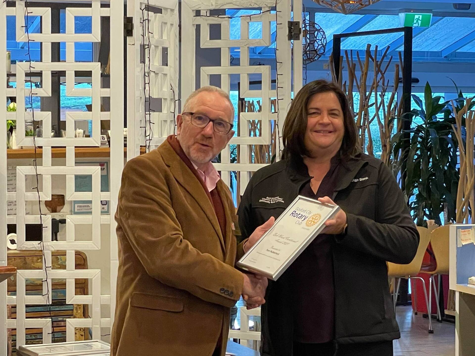 A man and a woman are shaking hands and holding a certificate.