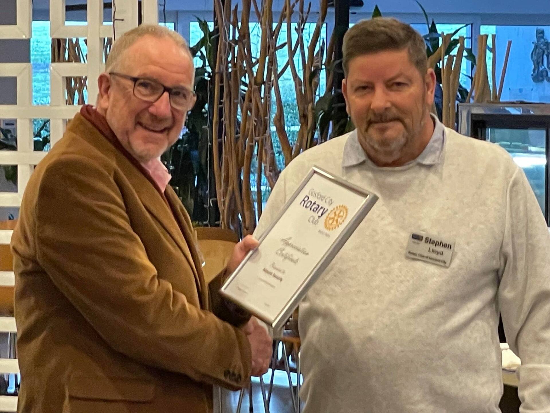 Two men shaking hands and one is holding a certificate