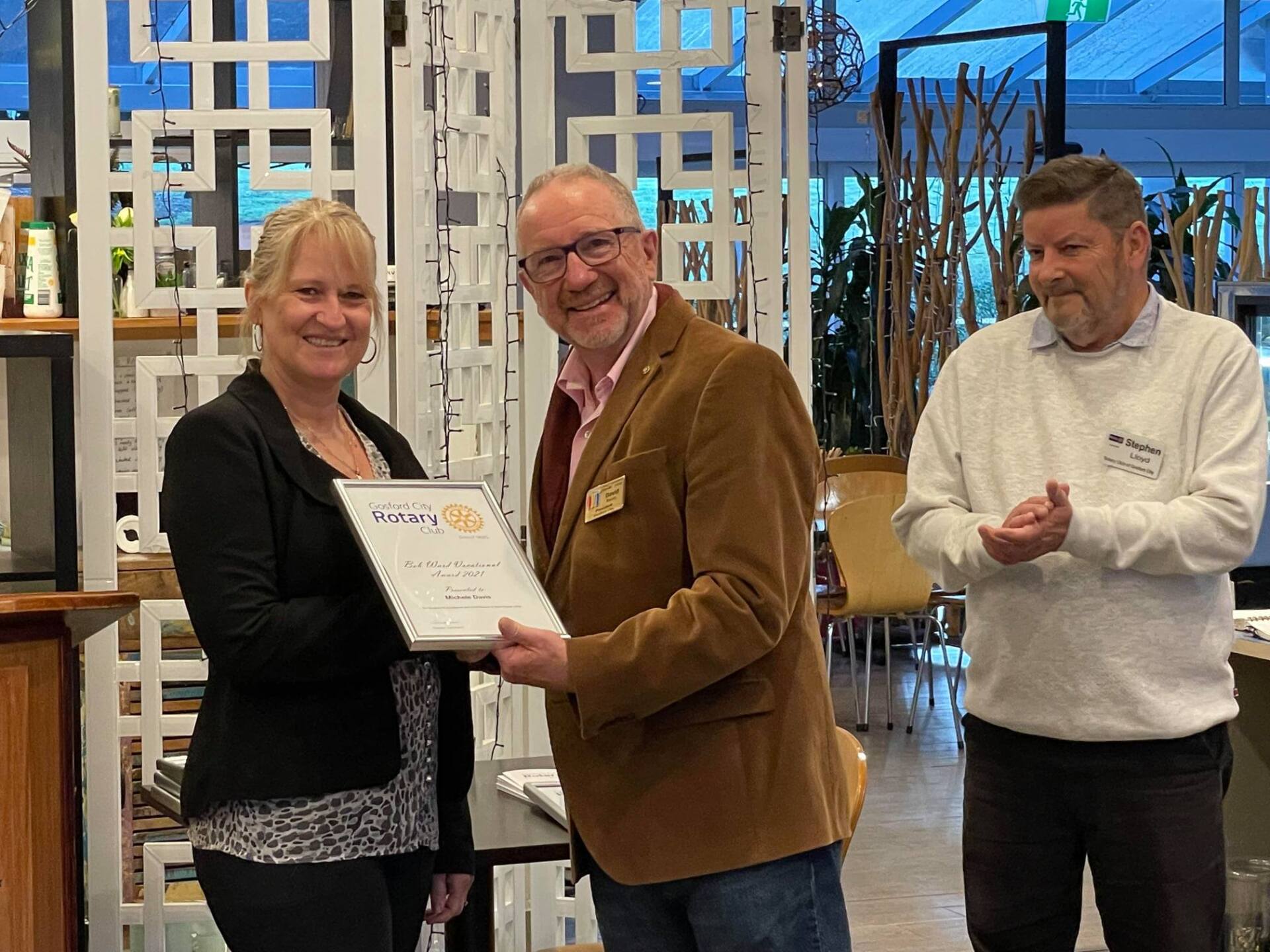 A man is giving a certificate to a woman in a room.