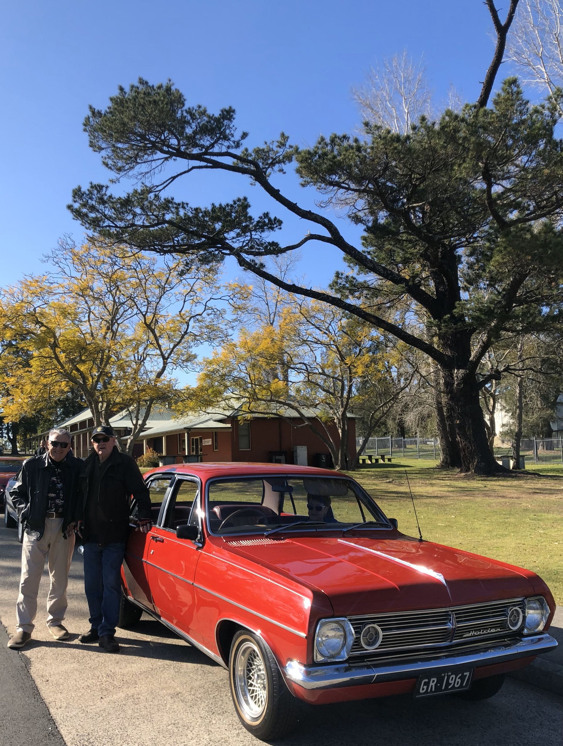 A couple of men standing next to a red car
