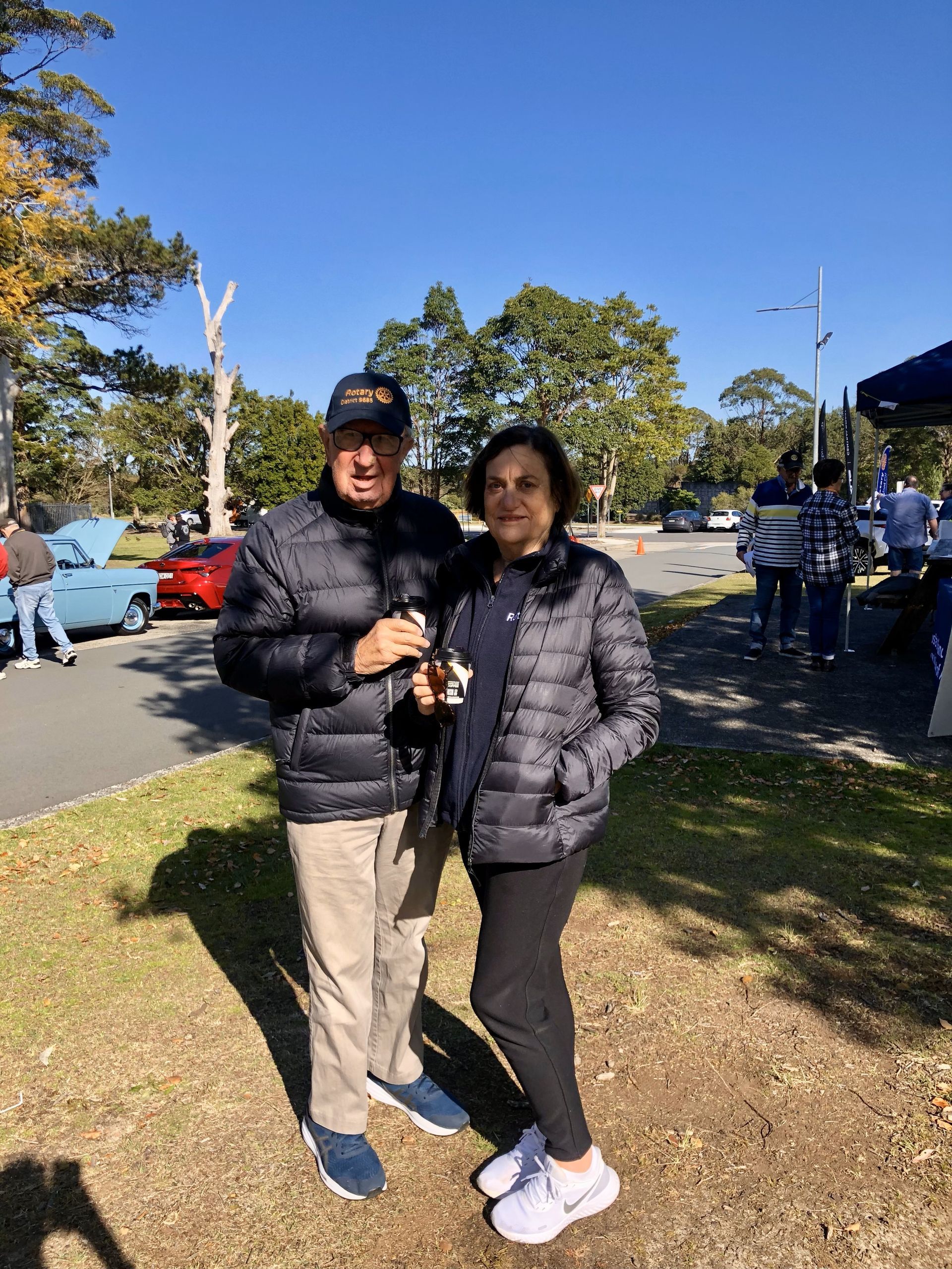 A man and a woman are standing next to each other in a park.