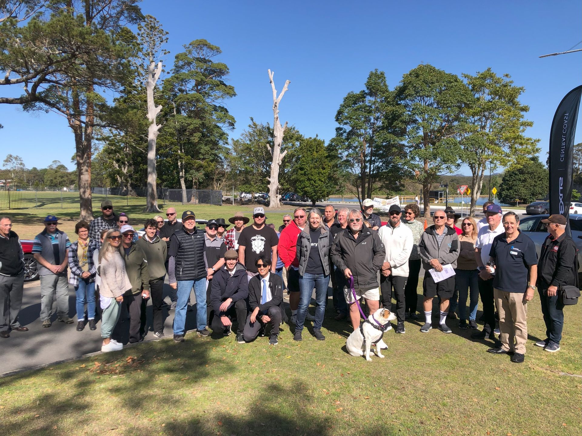 A large group of people are posing for a picture in a park.