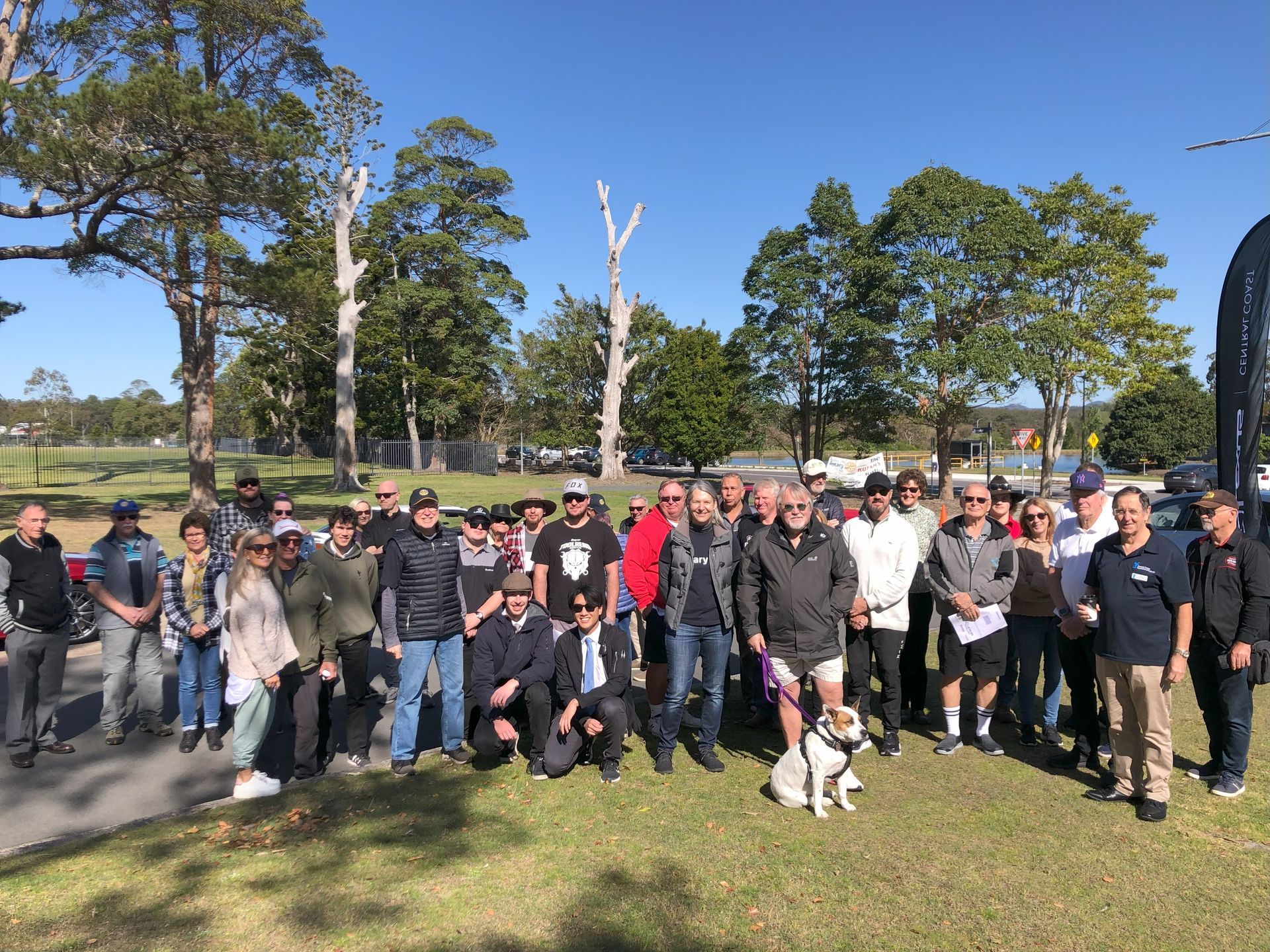 A large group of people are posing for a picture in a park.