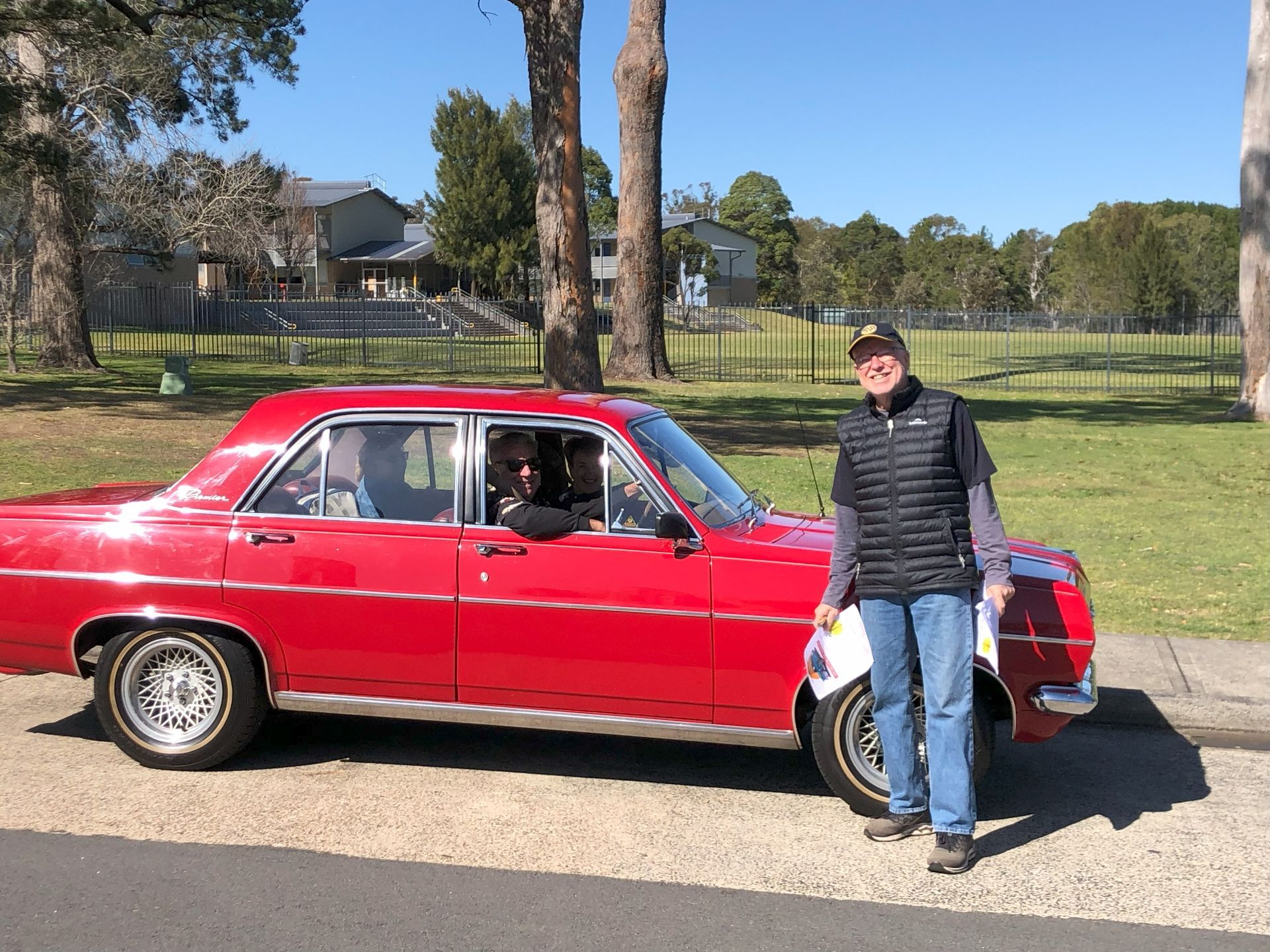 A man is standing in front of a red car.