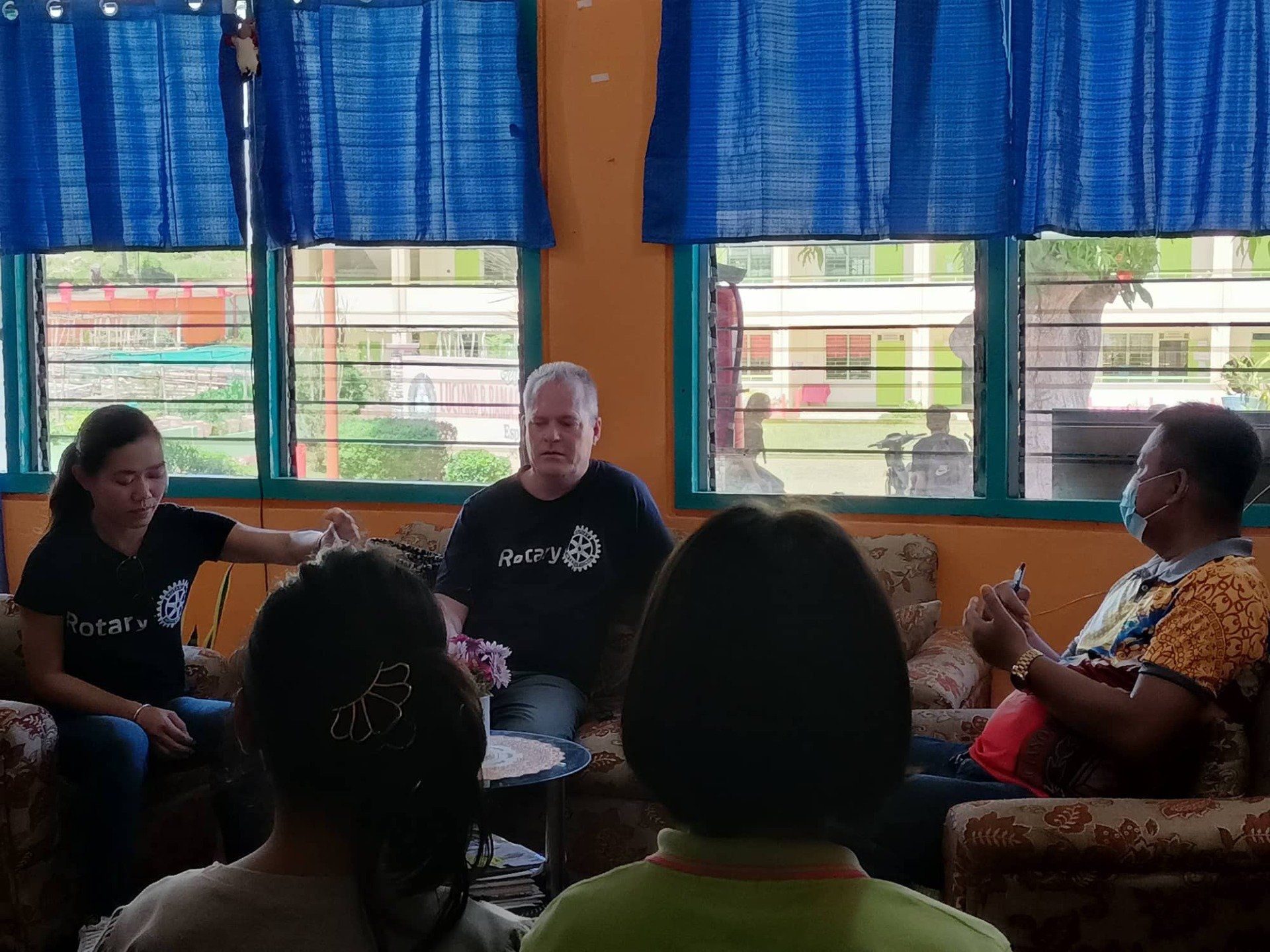 A group of people are sitting in a circle in front of a window.