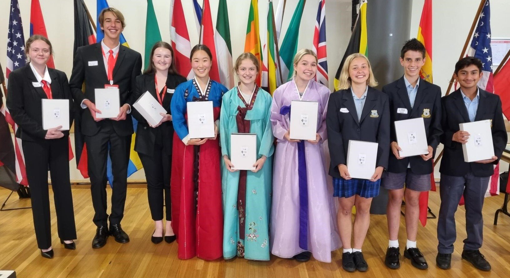A group of people standing in front of flags holding papers