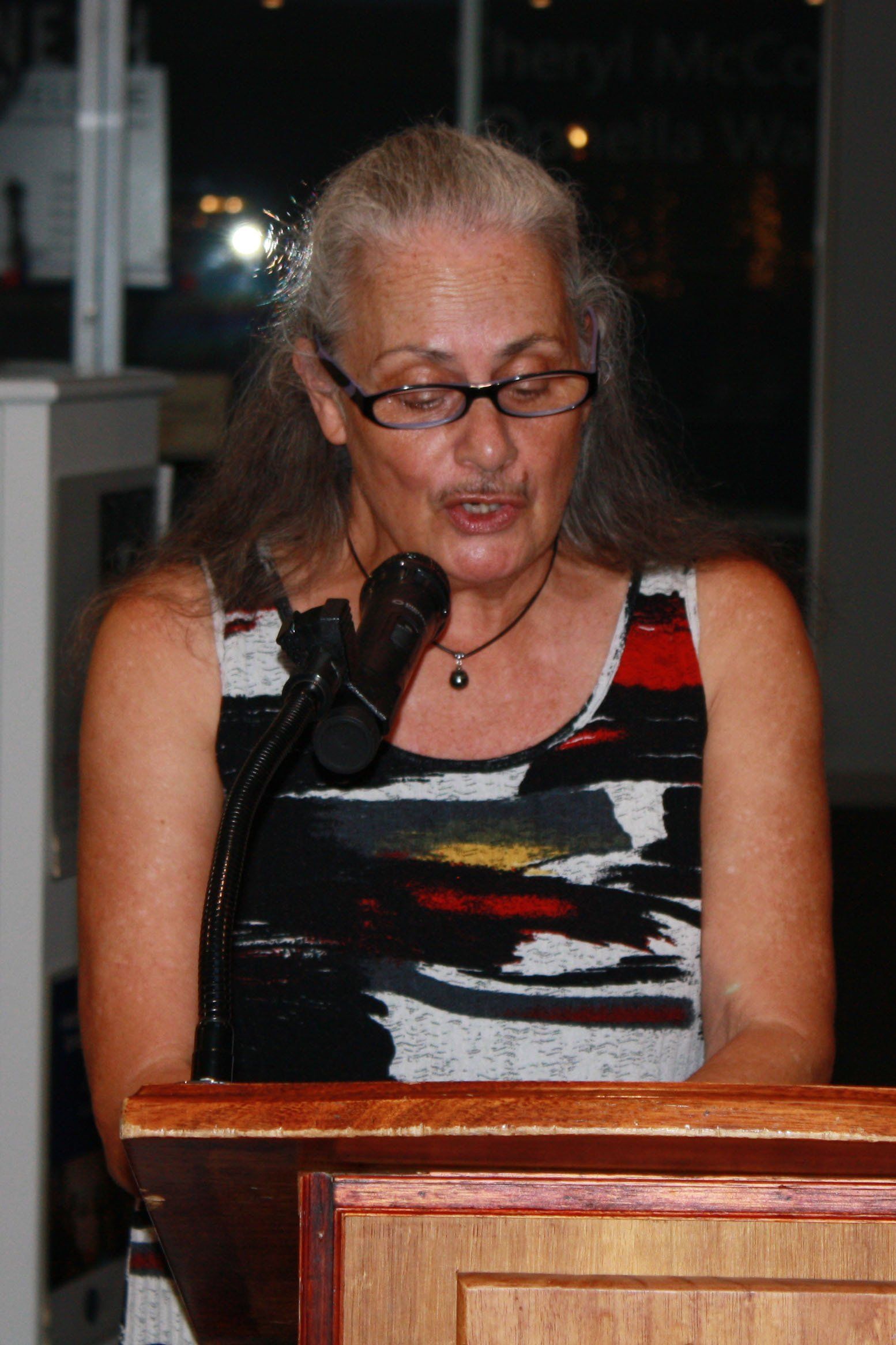 A woman is standing at a podium speaking into a microphone.