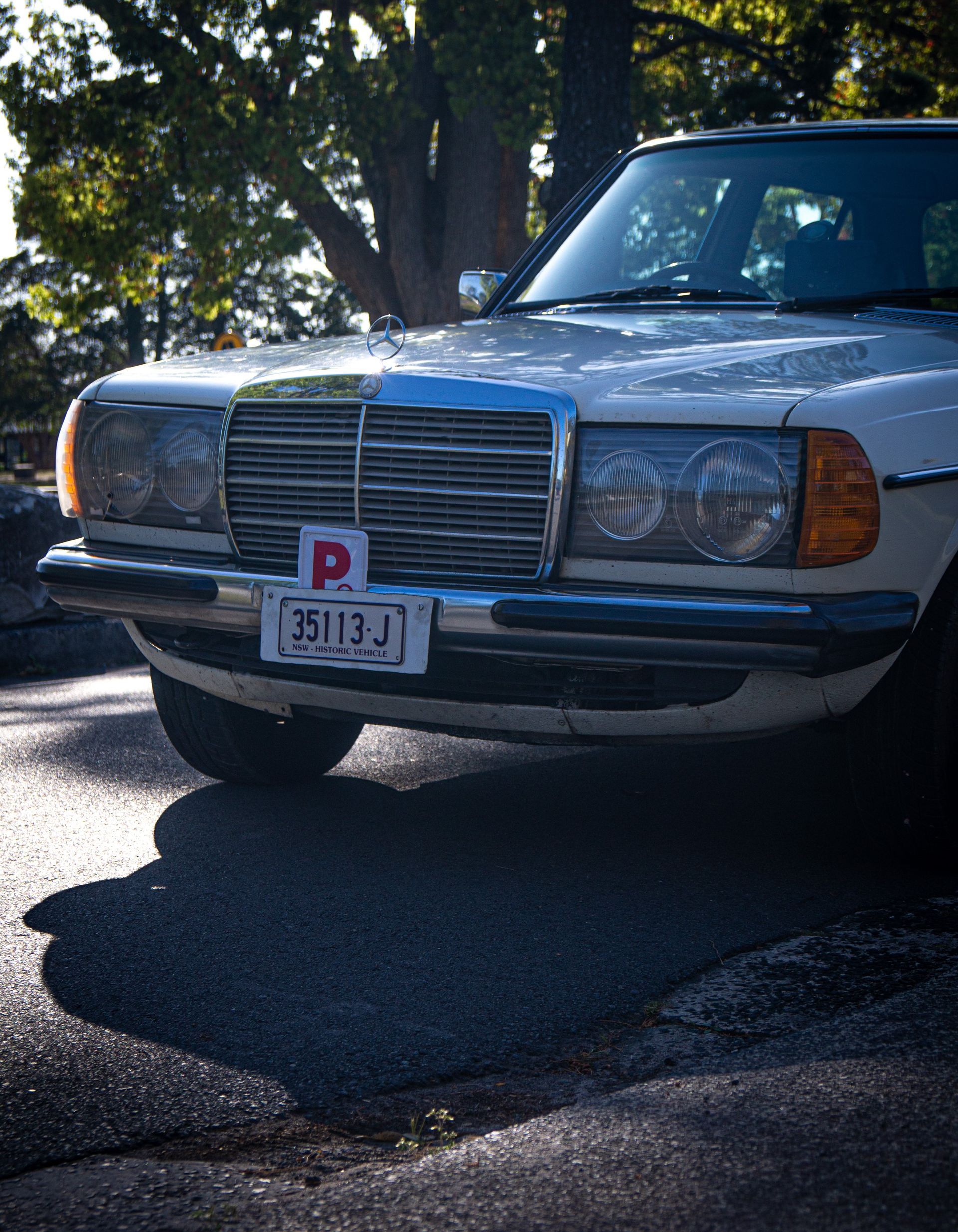 A white car with a license plate that has the letter p on it